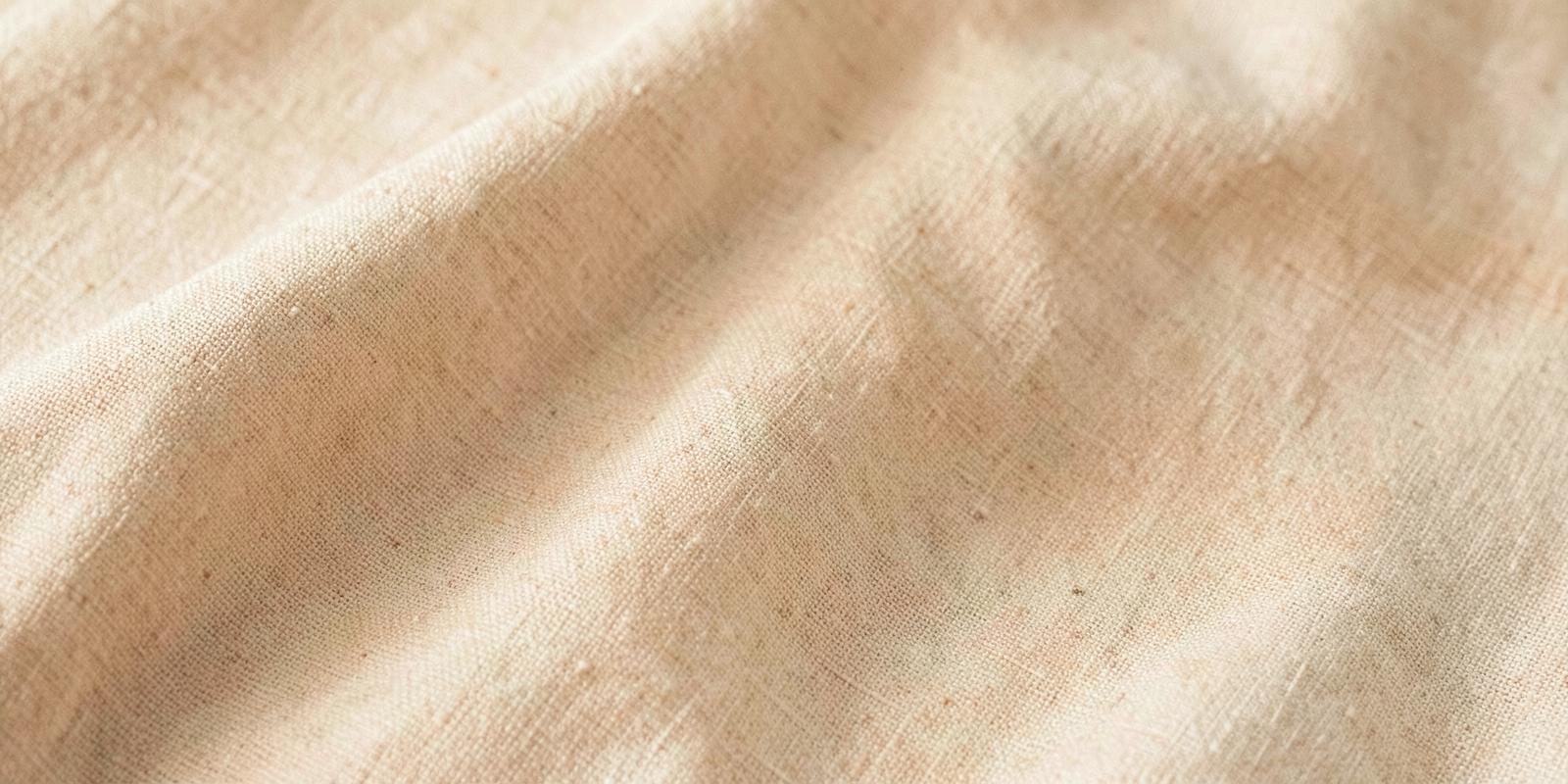 Soft folds of oatmeal linen in warm light, an abstract texture